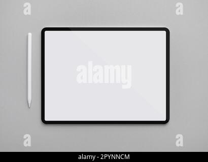 Digitales Tablet mit leerem weißem Bildschirm und Eingabestift auf grauem Papierhintergrund. Flach verlegt. Stockfoto