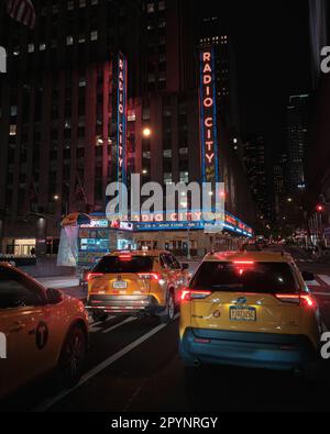 Gelbe Taxis und Radio City Music Hall Neonschild bei Nacht, Manhattan, New York Stockfoto