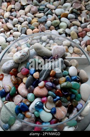 Runde Glasvase mit farbigen Mineralien und Flachbox mit Blick auf Meeressteine von oben Stockfoto