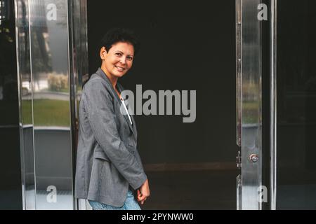 Eine schöne braune Frau mittleren Alters steht vor der Tür. Stockfoto