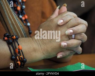 Peru, 04/05/2023, Hands and Seed Armbelet von Yanet Velasco Castillo, Schatzmeister des Verwaltungsrats der Ureinwohner des Ene-Flusses Asháninka, als die Führer indigener Amazonas den in Peru akkreditierten ausländischen Korrespondenten eine Pressekonferenz geben, Darüber, wie regionale und kommunale Regierungen den Vormarsch der Kokaanbaugrenze erleichtern, indem sie die Invasion ihrer Gemeinden legalisieren. In jüngster Zeit wurden viele einheimische Verteidiger des Amazonas ermordet, weil sie sich dem Kokaanbau und dem illegalen Holzeinschlag auf ihren Ländereien widersetzten und diese anprangerten. Stockfoto