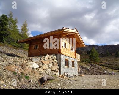 Kleine Almhütte/Schutzhütte aus Holz inmitten einer malerischen Bergszene Stockfoto