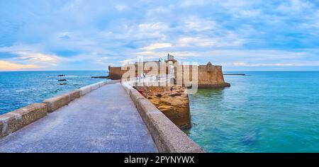 Panoramablick auf die mittelalterliche Burg San Sebastian, Steindeiche und blaues Wasser des Atlantiks bei bewölktem Sonnenuntergang, Cadiz, Spanien Stockfoto