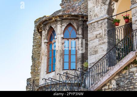 Alte mittelalterliche Burg mit langen Fenstern und einer Treppe, die von Schmiedeeisen umgeben ist Stockfoto