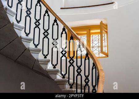 Kunstvoll verzierte Treppe mit schmiedeeisernem Geländer und Holzfenster Stockfoto