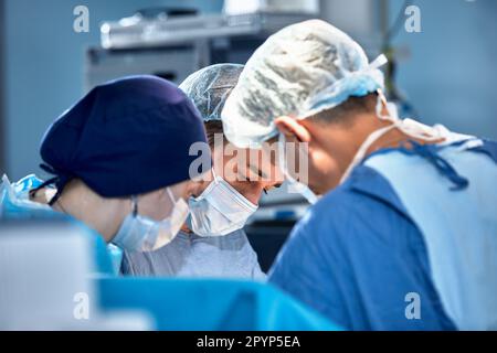 Gesichter von Chirurgen im Operationssaal während der Operation, moderne Medizin, medizinisches Personal während einer komplexen Operation, medizinische Wissenschaft, Nahaufnahme. Stockfoto