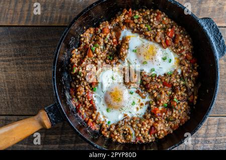 Gekochter Buchweizen mit Spiegeleiern, Paprika, Karotten und Zwiebeln, Nahaufnahme, Ukraine. Hintergrund für das Essen. Gesunde Ernährung Stockfoto