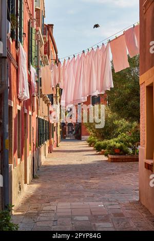 Wäscheservice wird an einem kleinen traditionellen und sehr bunten Ort auf der Insel Burano, Italien, getrocknet. Stockfoto