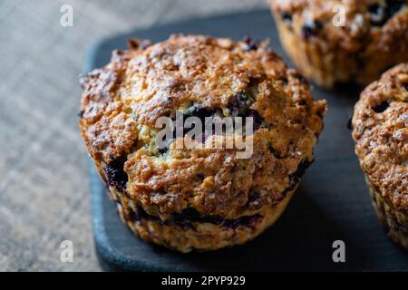Köstliche Muffins mit Blaubeeren auf einem Holztisch, Nahaufnahme. Süßes Gebäck auf dem Brett. Frische Cupcakes zum Frühstück Stockfoto