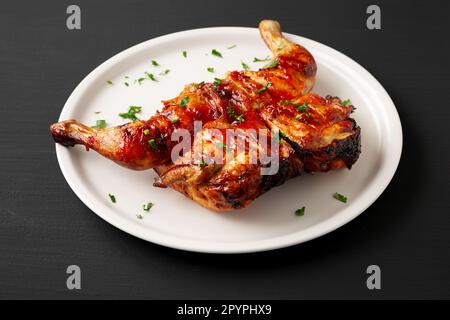 Hausgemachtes gegrilltes Piri-Piri-Hähnchen mit Petersilie auf einem Teller, Seitenansicht. Stockfoto