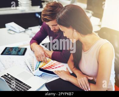 Hart arbeiten, um berufliche Ziele zu erreichen. Zwei junge Designer, die auf ein Farbmuster schauen. Stockfoto