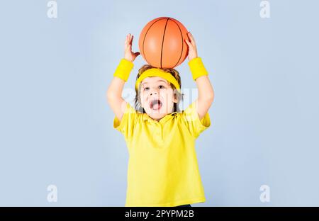 Kleiner Basketballer in Sportbekleidung. Ein Junge in Sportuniform, der Basketball spielt. Sportausrüstung. Kind mit Basketballball. Süßes kleines Stockfoto