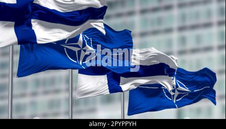 Brüssel, BL, April 2023: Die Flaggen Finnlands und der NATO winken im Wind. Finnland wurde am 4. April 2023 das 31. Mitglied der NATO. Anschauliche Bearbeitung Stockfoto