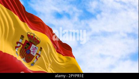 Die spanische Nationalflagge winkt im Wind an einem klaren Tag. Europäisches Land. Drei horizontale Streifen in Rot, Gelb, Rot, ein Wappen links Stockfoto