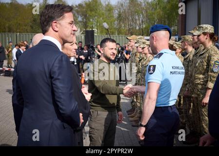 Soesterberg, Niederlande. 04. Mai 2023. Der ukrainische Präsident Volodymyr Zelenskyy, Mitte, begrüßt einen niederländischen Luftwaffensoldaten als niederländischen Premierminister Mark Rutte, links, blickt auf das Camp New Amsterdam, 4. Mai 2023 im Soesterberg, Niederlande. Kredit: Pool Photo/Pressestelle Des Ukrainischen Präsidenten/Alamy Live News Stockfoto