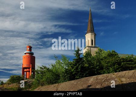 Alte Kirche und ein roter Leuchtturm in der Rocky Underground in Hanko Finnland an Einem wunderschönen sonnigen Sommertag mit klarem blauen Himmel Stockfoto