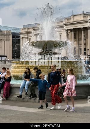 Am Trafalgar Square, London, am 30. April 2023 sitzen und spazieren gehen Stockfoto
