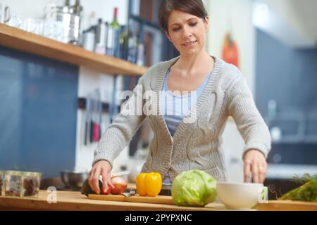 Ein köstliches Gericht von Grund auf zubereiten. Eine attraktive Frau, die Essen in der Küche zubereitet. Stockfoto