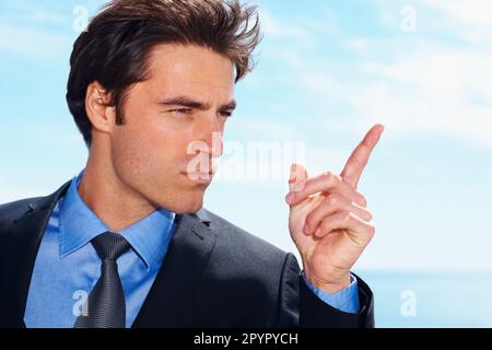 Geschäftlich autoritär. Junger, seriöser Mann, der mit dem Finger zeigt. Geschäftlich autoritär - eine Untersuchung eines jungen, seriösen Mannes, der mit dem Finger zeigt. Stockfoto