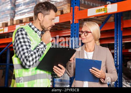 Manager und Arbeiter im Lager mit vielen Produkten Stockfoto