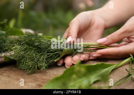 Frau mit frischen grünen Kräutern am Holztisch, Nahaufnahme Stockfoto