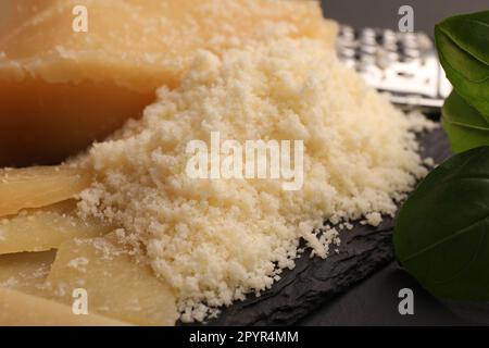 Köstlicher geriebener Parmesankäse auf schwarzem Schieferbrett, Nahaufnahme Stockfoto