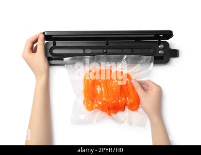 Frau, die Versiegelung für Vakuumverpackungen verwendet, mit Plastikbeutel mit Paprika auf weißem Hintergrund, Draufsicht Stockfoto