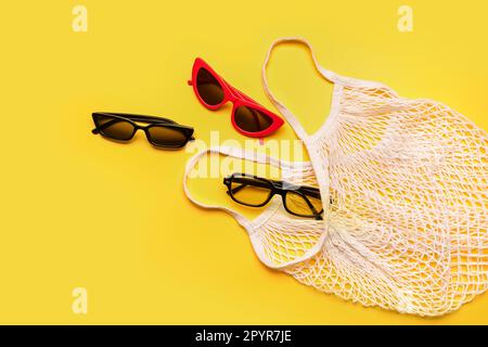 Tragetasche mit stilvoller Sonnenbrille auf gelbem Hintergrund Stockfoto