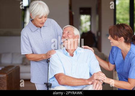 Es scheint, ich kann bald nach Hause gehen. Eine Krankenschwester, die ihrem älteren Patienten und seiner Frau gute Nachrichten überbringt. Stockfoto