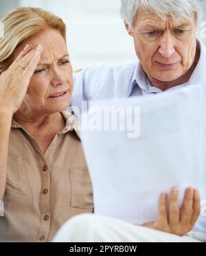 Das wird ein harter Monat. Ein älteres Ehepaar, das frustriert aussah, als es seinen Papierkram zusammen durchging. Stockfoto