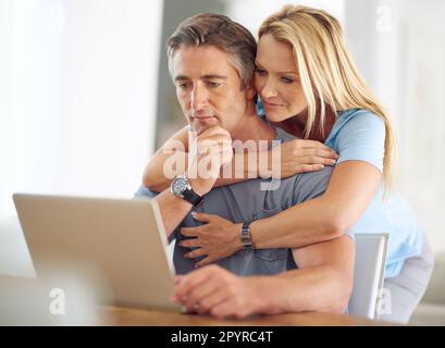 Soziale Netzwerke sind für jedes Alter geeignet. Ein glückliches, reifes Paar, das zu Hause ein Notebook benutzt. Stockfoto