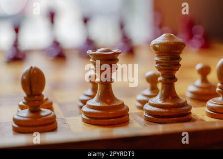 Selektiver Fokus auf hölzerne Schachfiguren auf hölzernen Schachbrettern und verschwommener Hintergrund des Fensters mit Licht. Stockfoto