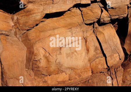 Ein flacher roter Sandstein mit Höhlenmalereien von antiken Künstlern, die Jagdszenen beschreiben. Berghütten, Chakassien, Sibirien, Russland. Stockfoto