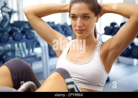 Sit-ups für einen starken Kern. Eine wunderschöne junge Frau, die im Fitnessstudio Sit-ups macht. Stockfoto