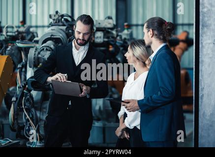 Der Eigentümer der Roboterfabrik erklärt und bespricht die Funktionalität und Leistung der Robotersysteme mit dem Kunden. Beantwortung von Fragen zum Kundendienst. Pric Stockfoto