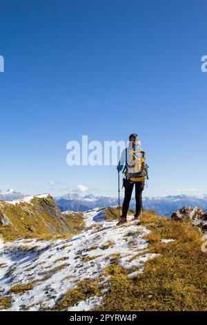 Rückansicht einer Wanderin auf dem Gipfel des Berges, die die AIPs unter dem blauen, sonnigen Himmel beobachten kann Stockfoto