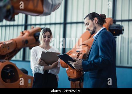 Der Eigentümer der Roboterfabrik erklärt und bespricht die Funktionalität und Leistung der Robotersysteme mit dem Kunden. Beantwortung von Fragen zum Kundendienst. Pric Stockfoto