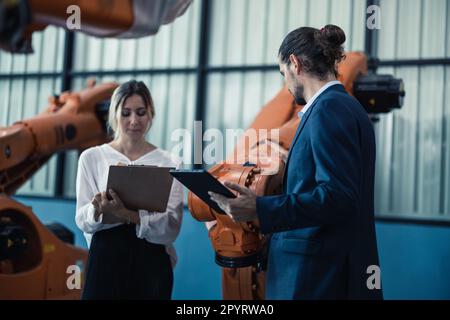 Der Eigentümer der Roboterfabrik erklärt und bespricht die Funktionalität und Leistung der Robotersysteme mit dem Kunden. Beantwortung von Fragen zum Kundendienst. Pric Stockfoto