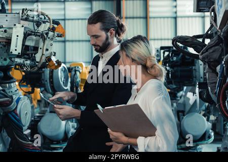 Der Eigentümer der Roboterfabrik erklärt und bespricht die Funktionalität und Leistung der Robotersysteme mit dem Kunden. Beantwortung von Fragen zum Kundendienst. Pric Stockfoto