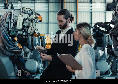 Der Eigentümer der Roboterfabrik erklärt und bespricht die Funktionalität und Leistung der Robotersysteme mit dem Kunden. Beantwortung von Fragen zum Kundendienst. Pric Stockfoto