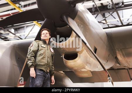 Armee, Jet-und-Mann-Pilot oder Kampfflugzeug oder niedriger Winkel vor Propeller und in Marinesuniform auf Asphalt. Militär, Düsenjäger und im Hangar oder Stockfoto