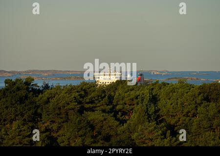 Göteborg, Schweden - August 25 2022: Stena-Fähre, die hinter Bäumen eines Waldes im Hafen ankommt Stockfoto