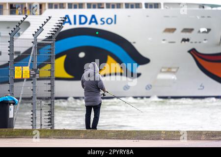 Göteborg, Schweden - Oktober 29 2022: Großes Kreuzfahrtschiff AIDAsol fährt ab, während Männer vom Dock fischen Stockfoto