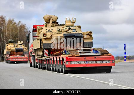 Außergewöhnlicher Ladetransport eines amerikanischen Militärpanzers M1 Abrams im Verkehr. Fahrzeugkonvoi mit drei Panzertransporten. Lieto, Finnland. 28. April 2023. Stockfoto