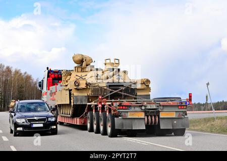 Außergewöhnlicher Ladetransport eines amerikanischen Militärpanzers M1 Abrams im Verkehr. Fahrzeugkonvoi mit drei Panzertransporten. Lieto, Finnland. 28. April 2023. Stockfoto