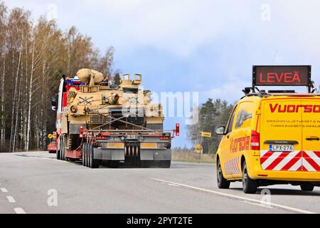 Außergewöhnlicher Ladetransport eines amerikanischen M1 Abrams Militärpanzers im Verkehr mit einem Begleitfahrzeug. Konvoi mit 3 Transporten. Lieto, Finnland. 28. April 2023. Stockfoto