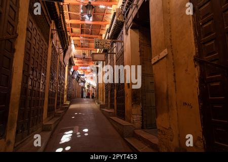 Fez, Marokko 2022: Historische und traditionelle enge Gassen von Fes el-Bali, der alten Medina, mit Geschäften des Souks (Suq) und Menschen Stockfoto