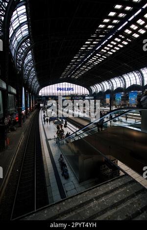 Eine Vertikale eines belebten Bahnhofs mit mehreren Bahnhöfen, die mit Pendlern auf dem Weg zu und von ihrem Ziel gefüllt sind Stockfoto