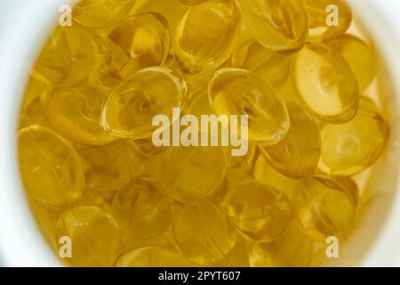 Viele gelbe Gelatinekapseln auf hellem Hintergrund. omega Viramins, Nahaufnahme, Makro. Stockfoto