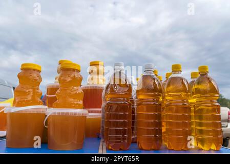 Landwirtschaftsmesse im Herbst. Kunststoffbehälter mit Bienenhonig und Flaschen Sonnenblumenöl Stockfoto
